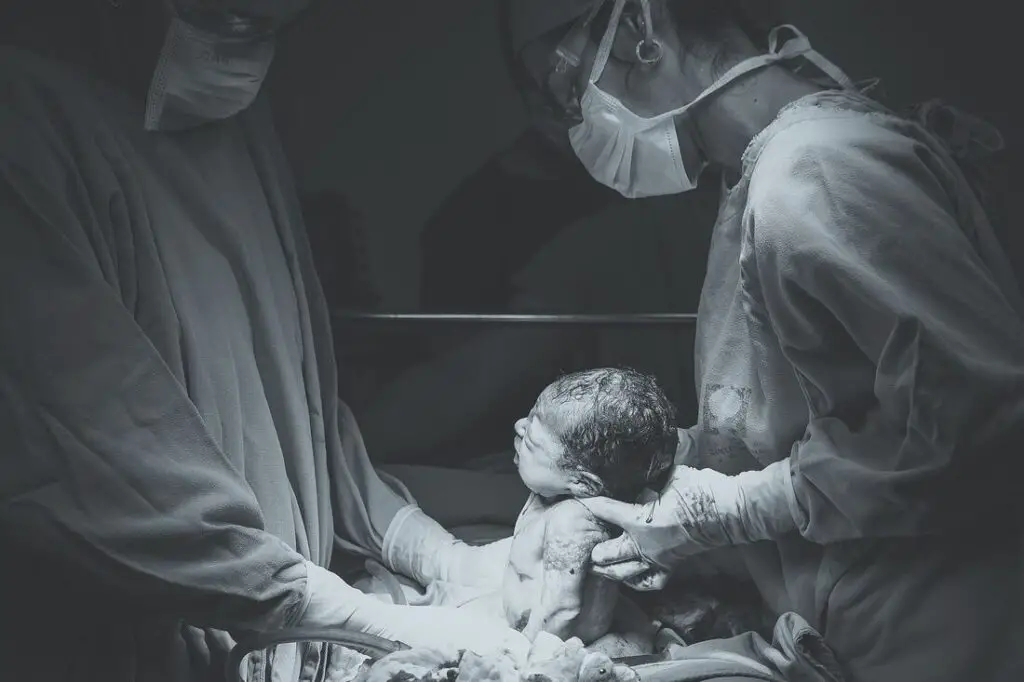 bebê recém nascido, entre dois profissionais da saúde. Para ilustrar conteúdo mensagens para bebê que vai nascer.