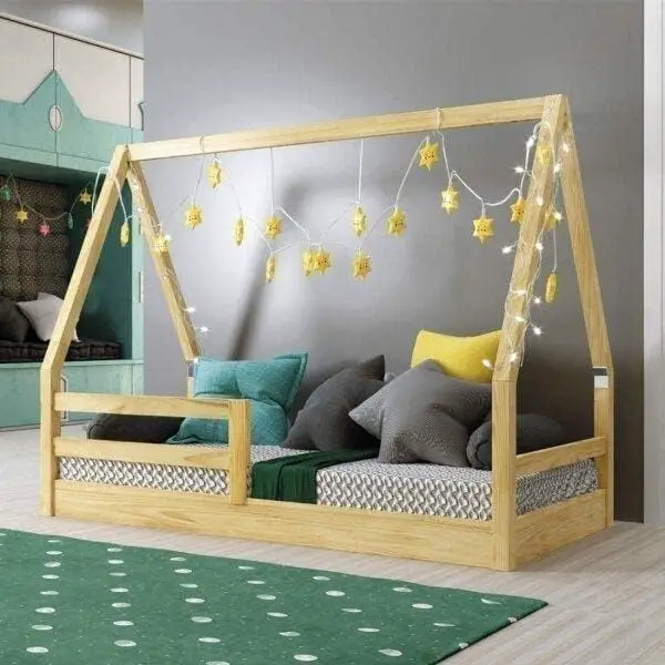cama montessoriana, com enfeites de estrelas amarelas e luzes piscantes, em um quartocom tapete verde