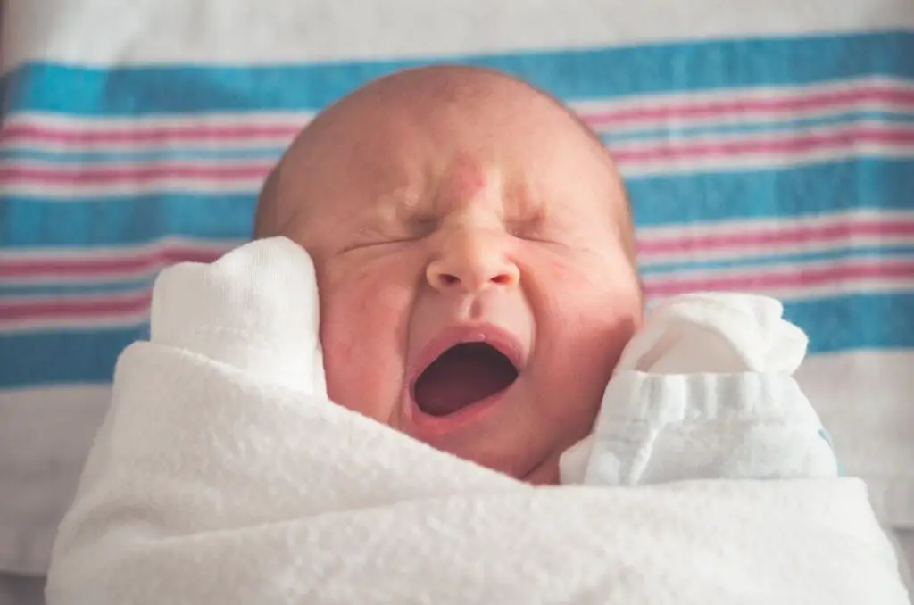 bebê recém nascido com a boca aberta e olhos fechados, imagem para ilustrar o texto sobre rotina do sono do bebe