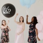 tres mulheres, sendo que a do meio está grávida segurando um balão escrito "boy or girl" em uma festa de chá revelação simples