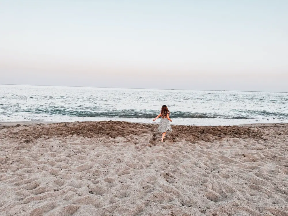 imagem de costas de menina correndo em direção ao mar, na praia. Para ilustrar post nomes gregos femininos