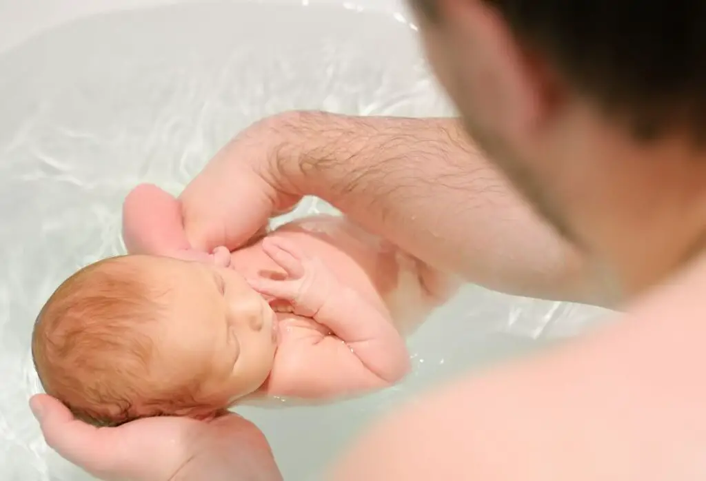 imagem de pai dando banho em recém nascido.