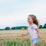 menina andando e sorrindo em campo, para capa do post Nomes Americanos Femininos