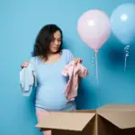 Woman holding a blue onesie in one hand and a pink onesie in the other, in a gender reveal games
