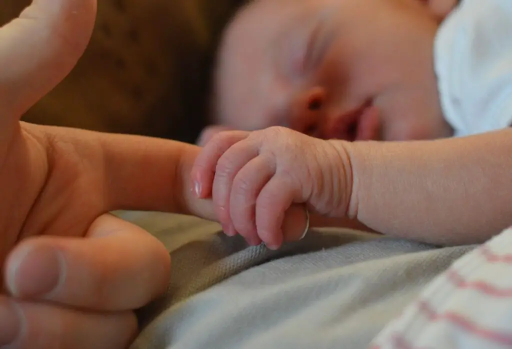 bebê segurando a mão de uma pessoa