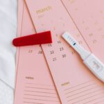um teste de gravidez positivo sobre um calendário rosa. Calculadora Gestacional