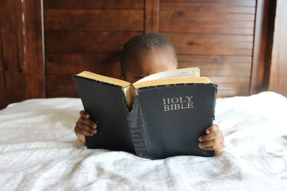 menino deitado em uma cama, com uma bíblia, nomes bíblicos masculinos