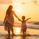 mãe e filha andando na praia, de costas, sol se pondo, mensagens de dia das mães emocionantes