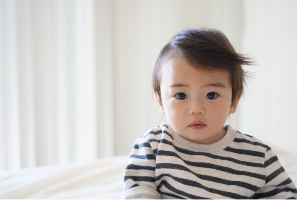 Image of a Japanese boy approximately 2 years old, wearing a black and white striped shirt to illustrate the post about Japanese Boy Names.