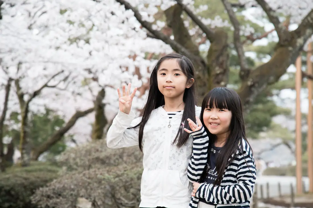 Two Japanese girls in front of a tree, cover of the post about Japanese girl names.