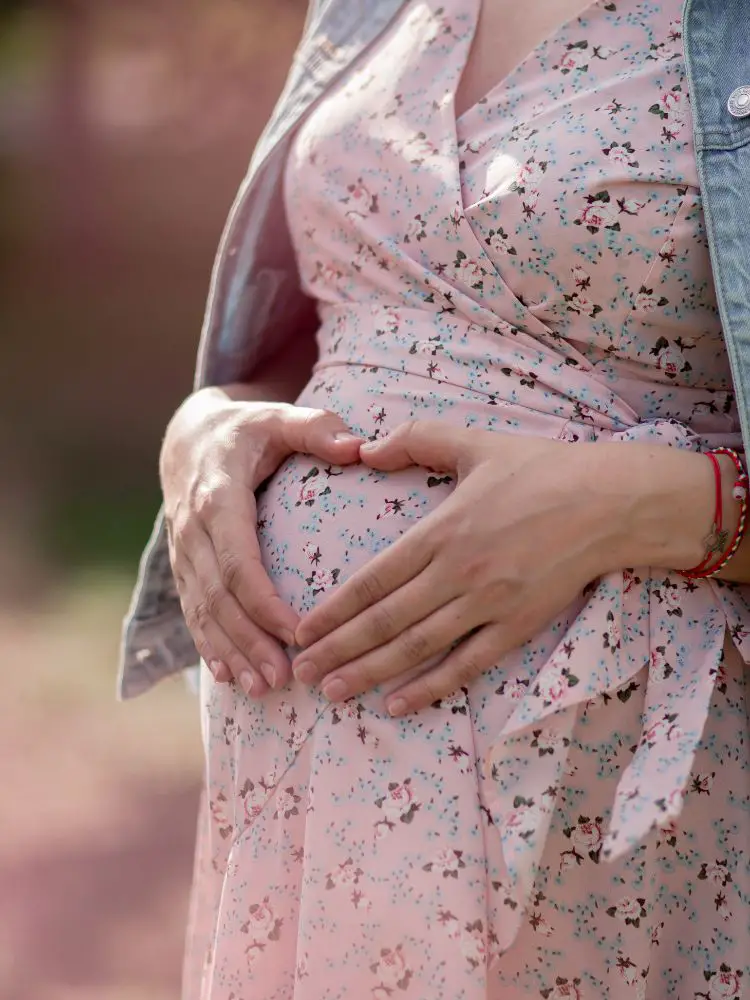 imagem de uma mulher segurando a barriga, com as mãos em forma de coração, mensagem para desejar um bom parto.