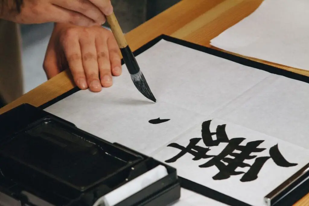 Image of a brush with a person practicing shodo, Japanese calligraphy, to demonstrate the structure of Japanese girl names.